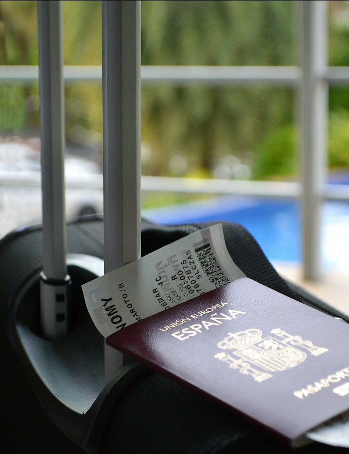 Passport and boarding pass beside a suitcase at a tropical pool