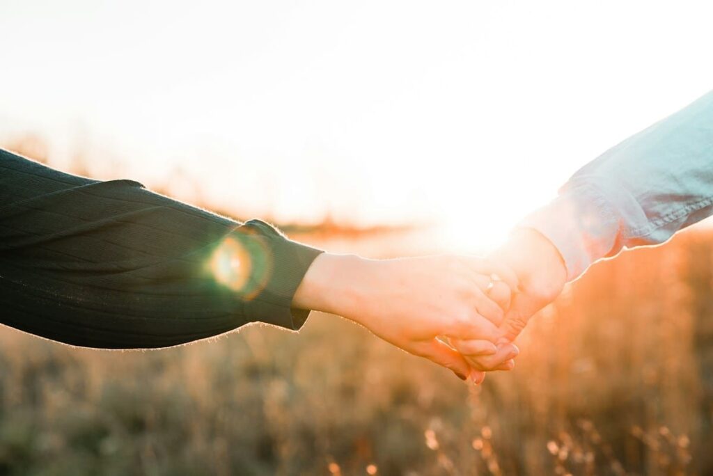 Two hands held together at sunset, a gentle reminder that chlamydia and gonorrhoea testing protects partners too