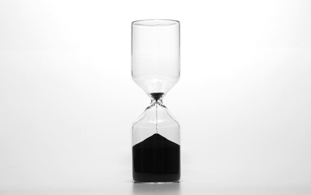 Hourglass with dark sand running through, illustrating the HIV window period before a test can detect infection