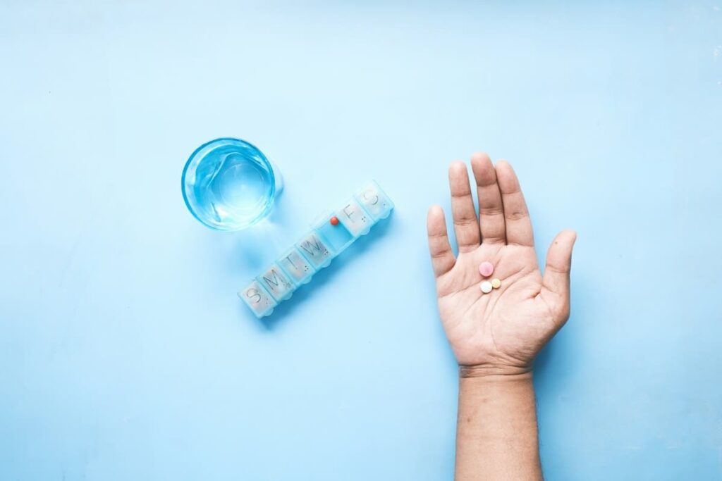 Open hand holding a tablet beside a glass of water, representing daily HIV PrEP