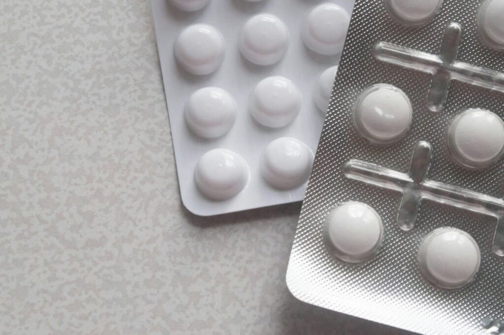 Pill blister strips on a table, comparing HIV prevention options with PEP effectiveness