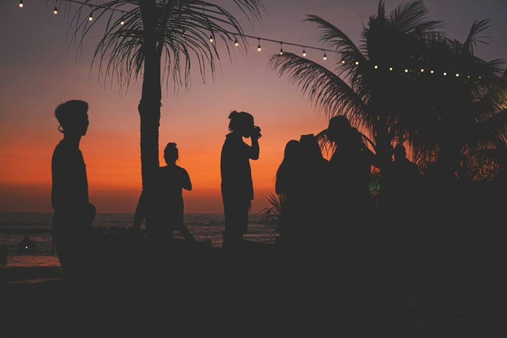 Friends silhouetted on a beach at sunset, planning a safer night out on the islands