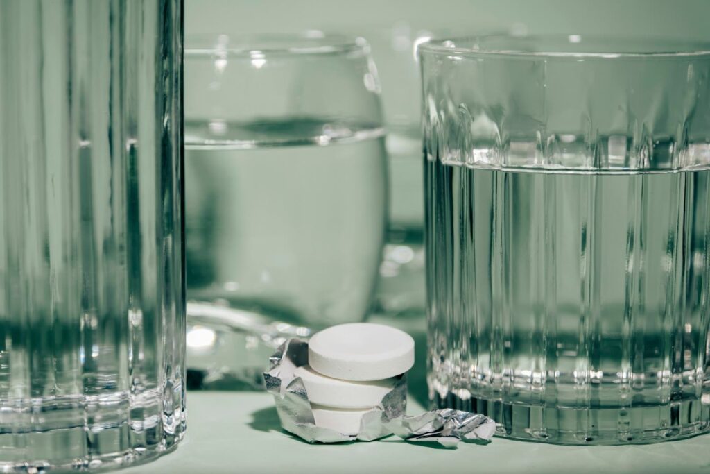 Glass of water beside tablets on a bedside table, representing managing PEP side effects at home