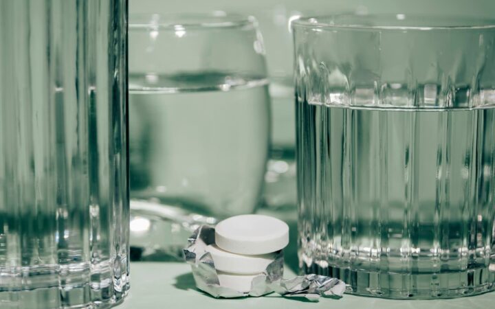 Glass of water beside tablets on a bedside table, representing managing PEP side effects at home