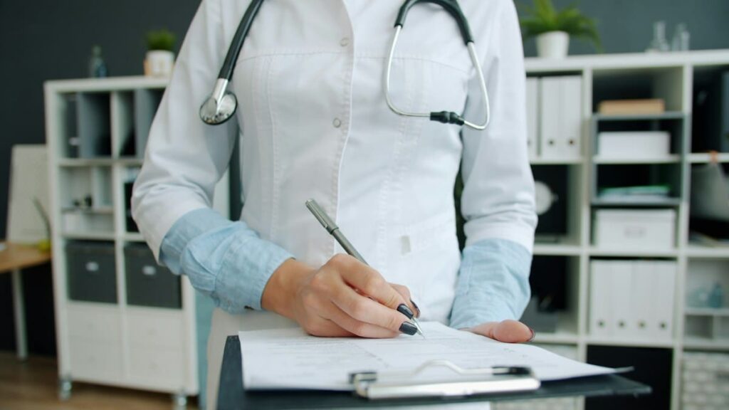 Doctor writing on a prescription pad during a consultation about starting HIV PrEP