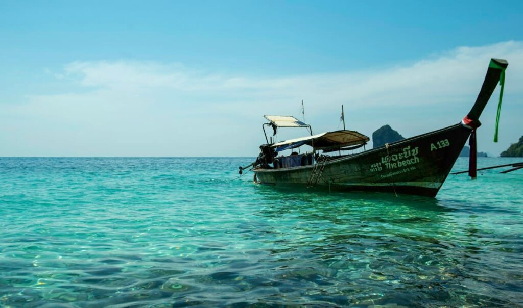 Longtail boat on turquoise water near a tropical island, where travellers can still access sexual health care
