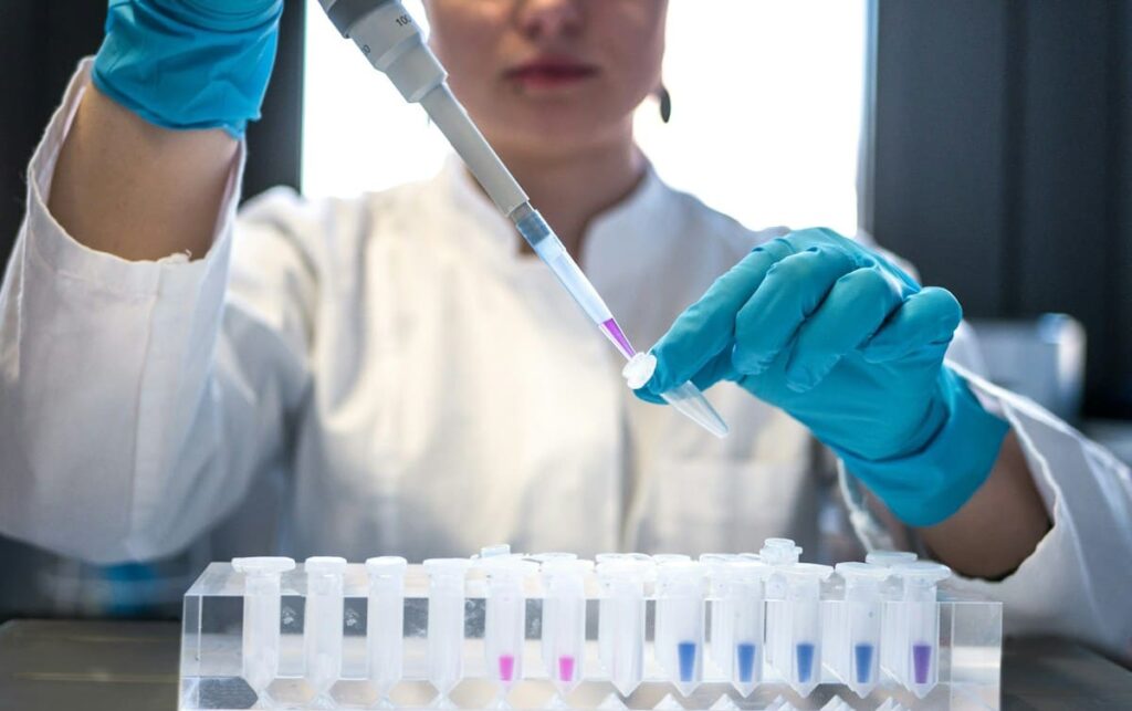 Laboratory worker holding a swab sample tube, as used for chlamydia and gonorrhoea STD tests after unprotected sex