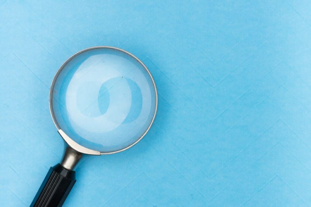 Magnifying glass on a blue background, representing a close look at the stages of syphilis and their signs