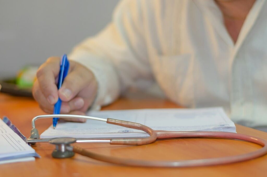 Doctor writing notes on a clipboard during an assessment after a possible unsafe tattoo needle
